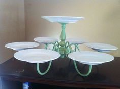 there are many plates on the table with one candle holder in front of them and four to the side