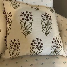 two pillows sitting on top of a bed next to each other with flowers on them