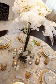 the table is set with white flowers and place settings