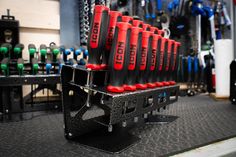 there are many black and red tools on the rack in the shop, including wrenches