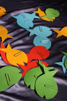 colorful fish cut out from paper on a black cloth with the letters d and f