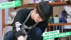 a young man sitting on top of a table next to a green and white sign