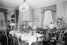 an old black and white photo of a dining room with halloween decorations on the table