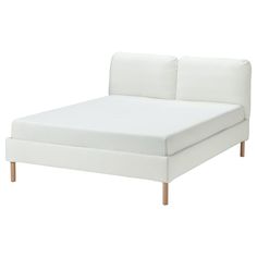 a white bed with wooden legs and headboard