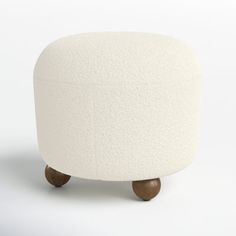 a white ottoman sitting on top of a wooden base