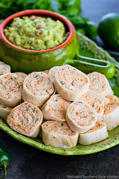 there are many rolls on the plate with guacamole and salsa in the bowl