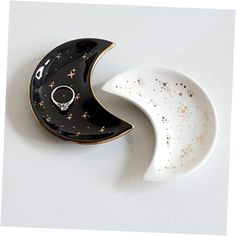 two ceramic moon dishes sitting next to each other on a white surface with gold speckles