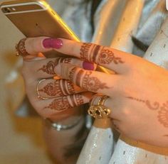 a woman with henna on her hands holding a cell phone