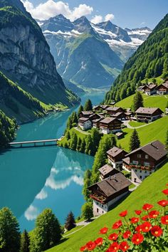 a scenic view of a mountain village with flowers in the foreground and a river running through it