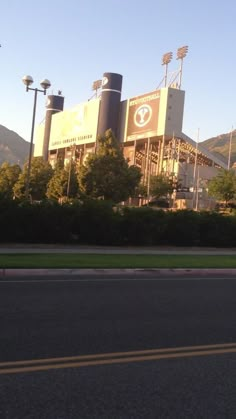 a baseball stadium with mountains in the background and trees on either side of the road