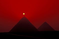 the sun is setting behind three pyramids