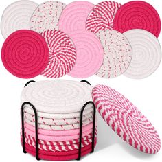 a stack of pink and white coasters next to a basket filled with red and white towels