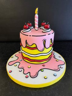 a pink and yellow birthday cake sitting on top of a table