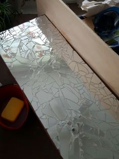 a broken glass table with a red bowl on it and some other items in the background