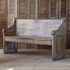 an old wooden bench sitting on top of a hard wood floor next to shutters