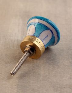 a blue and white ceramic knob with a screw in the middle on a gray surface