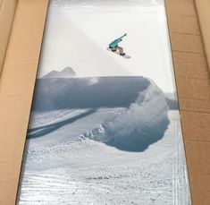 a man flying through the air while riding a snowboard in front of a box