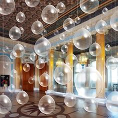 an image of bubbles floating in the air over a room with columns and chandelier