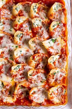 a casserole dish filled with shells covered in marinara sauce and parmesan cheese