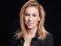 a woman with blonde hair and blue eyes posing for a photo in front of a black background