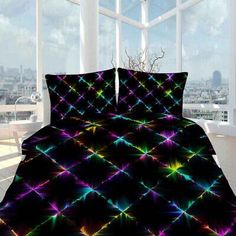 a bed covered in a black comforter with multicolored stars on the cover