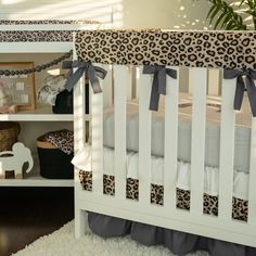 a baby crib with a leopard print and grey bedding