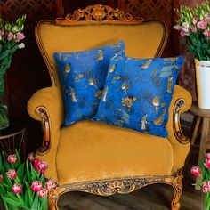 a chair with two pillows on it in front of some flowers