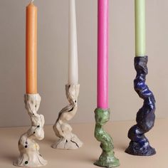 three candles are lined up next to each other in different colors and shapes, with one candle sticking out from the top