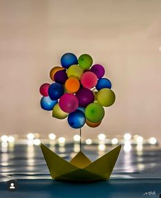 an origami boat with balloons floating on the water