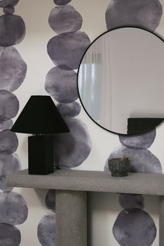 a mirror sitting on top of a table next to a lamp and a black vase