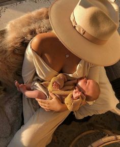 a woman holding a baby in her arms and wearing a hat on top of it