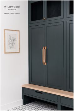 a black cabinet with wooden handles and drawers in a white walled room next to a painting on the wall