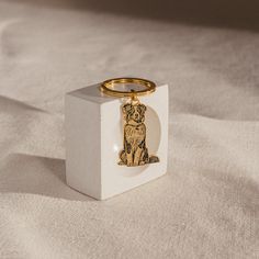 a white block with a gold dog keychain sitting on it's side