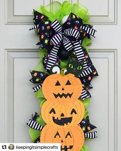 a halloween wreath with two pumpkins and black cats on it, hanging from the front door