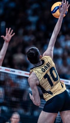 a volleyball player reaching up to hit the ball with his racket in front of him