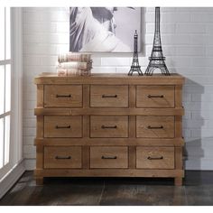 a wooden dresser sitting in front of a window next to a painting on the wall