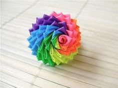 a multicolored paper flower sitting on top of a wooden table next to scissors