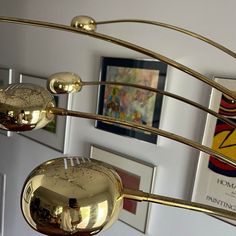 three golden spoons hanging from the ceiling in a room with pictures on the wall