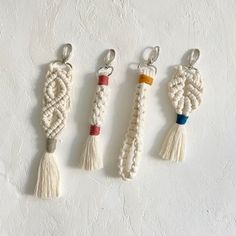 four tasselled keychains hanging on a white wall