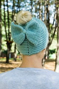 a woman wearing a blue knitted hat with a big bow