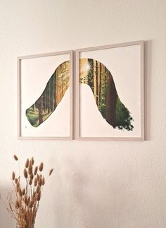 two paintings hanging on the wall next to a vase with dried flowers in it and one has an image of a forest