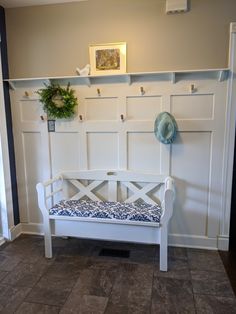 a white bench sitting in front of a wall with hooks on it's sides