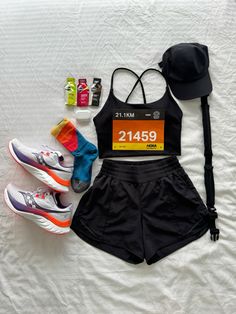 a woman's running outfit, hat, and shoes on a bed with white sheets