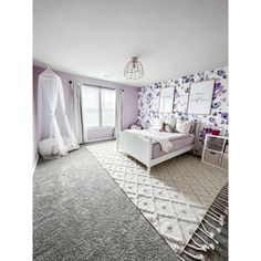 a bedroom decorated in lavender and white with floral wallpaper, bedding, rugs and curtains