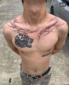 a man with tattoos on his chest standing next to a car