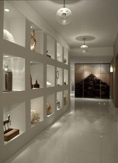 a long white room with shelves filled with vases