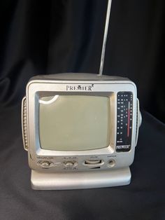 an old fashioned television sitting on top of a black cloth covered table next to a remote control