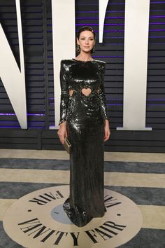 a woman in a long black dress standing on a white and grey carpet with the words vanity