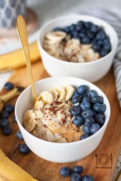 two bowls of oatmeal with bananas and blueberries on a cutting board