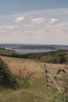 a wooden fence sitting on top of a lush green hillside next to a field filled with grass